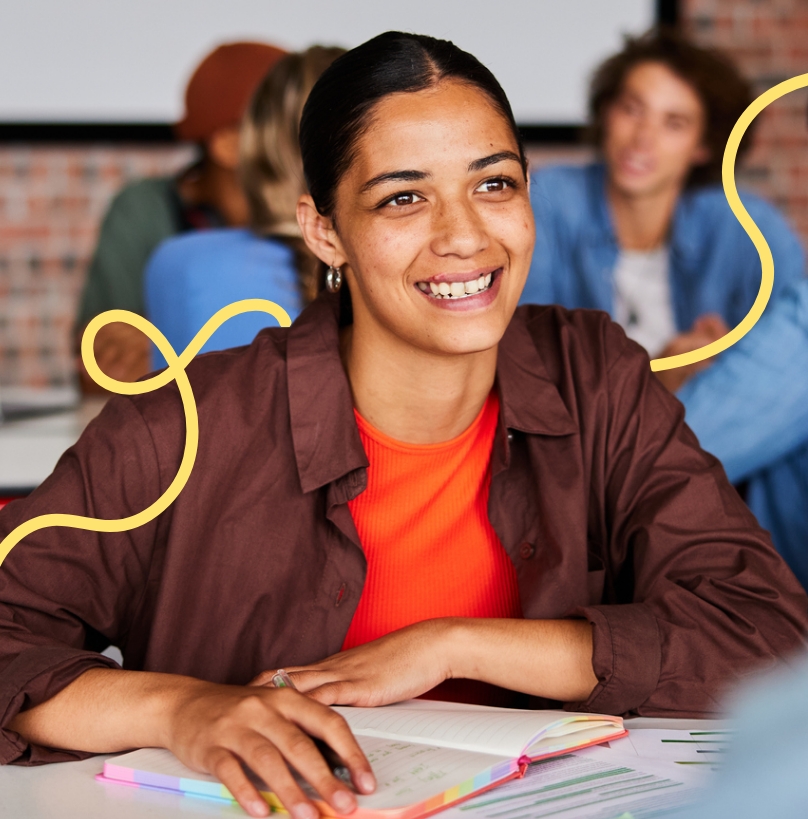 Smiling student sitting at a desk with a notebook.